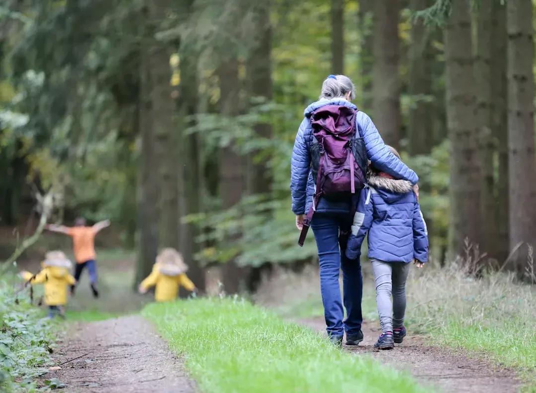 group of people walking in a serene forest with tall trees